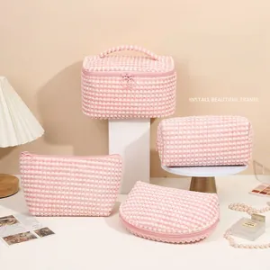 Pink and white fuzzy plush makeup bag set with checkerboard texture on stone pedestal
