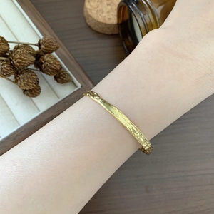 Detailed close-up of textured gold S925 silver bangle with irregular hammered surface pattern