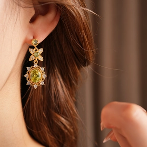 Détail de boucles d'oreilles vintage en or avec zircons verts sur mannequin