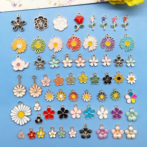 Assorted colorful enamel flower alloy pendants for DIY jewelry making on blue background