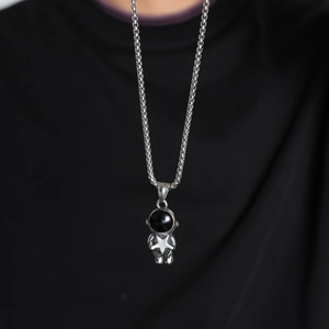 Detail of a silver astronaut pendant with black visor on a stainless steel chain