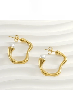 Detailed view of 18K gold irregular geometric earrings featuring a single white pearl
