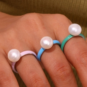 Detail of colorful drip oil stackable rings featuring white pearls on a hand
