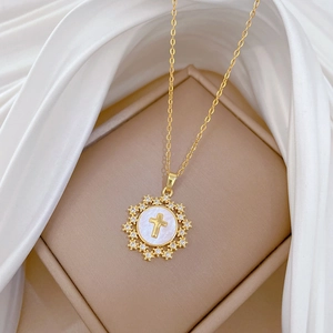Detail of star cross necklace with zircon inlay on white shell pendant over silk fabric