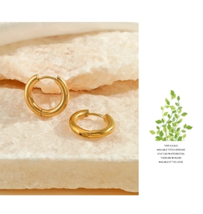 Close-up of gold geometric hoop earrings with polished finish on a stone surface