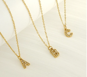 Close-up of gold plated initial necklaces A B C with shimmering pave crystal stones