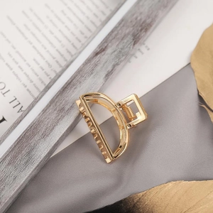 Detail of a large golden metal hair claw clip with pearls on elegant fabric