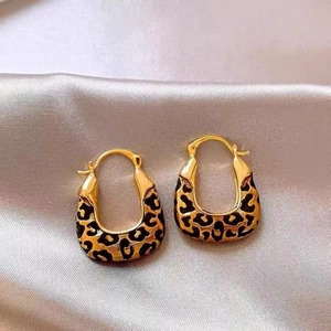 Close-up of leopard print gold-plated U-shaped hoop earrings on purple silk fabric