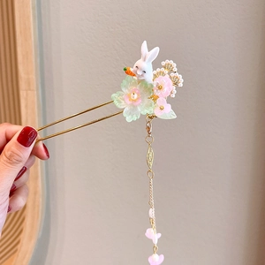 Detailed close-up of a U-shaped gold hairpin with a cute rabbit and floral charms