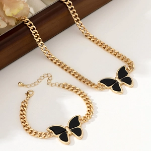Detail of gold curb chain necklace and bracelet set with black butterfly pendants