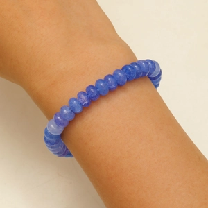 Détail macro du bracelet en perles bleues avec texture craquelée et pendentif papillon