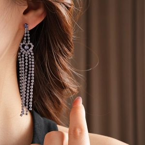 Vue détaillée de boucles d'oreilles à longs pompons en strass violets portées par un mannequin