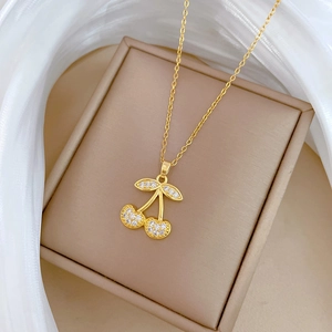 Detail of cherry pendant necklace with sparkling zircons on a soft beige jewelry box