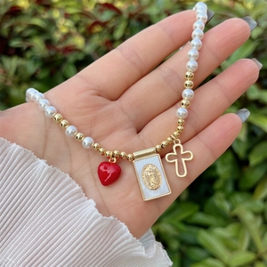 Detailed view of 18K gold plated necklace with pearls, red heart and Virgin Mary pendant