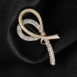 Macro shot of gold ribbon brooch with sparkling rhinestones on black leather texture