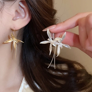 Detail of orchid-shaped dangle earrings in gold and silver finish with tassels