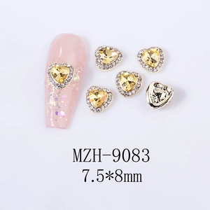 Macro detail of 7.5x8mm yellow heart nail gems with small rhinestones on a pink base