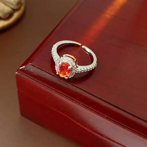 Macro detail of silver ring with oval orange zircon stone in classic wooden jewelry box