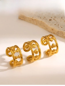 Detailed close-up of gold butterfly, shell, and heart rings on textured stone