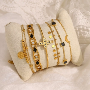 Ensemble de bracelets dorés multicouches avec trèfle, lune et pierre noire sur tissu