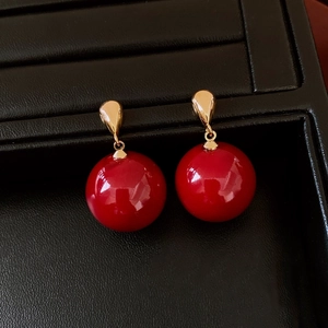 Detailed view of red strawberry drop earrings with shiny golden studs and round pendants