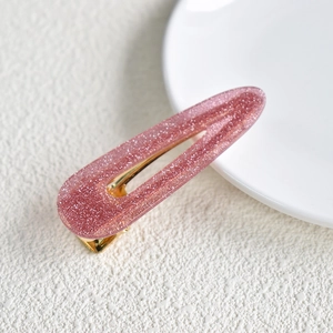 Close-up of a pink glitter snap hair clip with a stylish starry teardrop design