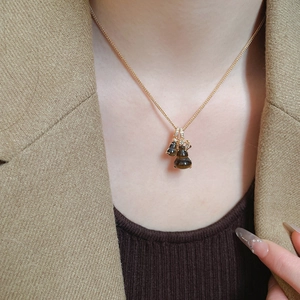 Close-up of golden gourd pendant necklace with tiger eye stones and crystal inlay