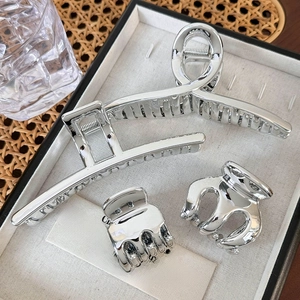 Close-up of polished silver metal hair claw clips set in a wooden jewelry gift box