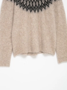 Dettaglio del maglione in maglia di alpaca beige con motivo jacquard geometrico sullo scollo