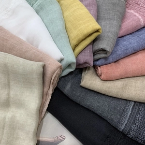 Folded cotton linen scarves in various colors featuring elegant lace trim details