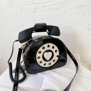 Macro detail of glossy black patent leather vintage telephone bag with heart dial