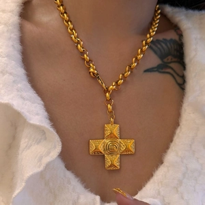 Macro view of 18k gold plated vintage cross pendant with embossed spiral texture