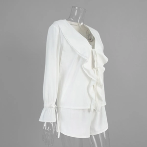 Detail view of cotton set with ruffled v-neckline and elastic cuffs on white blouse