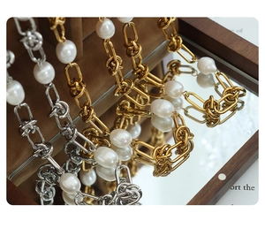 Detail of twisted gold and silver necklaces with freshwater pearls on a mirror