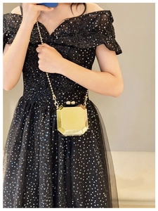 Octagonal gold metal clutch bag with chain strap held by model in sequin dress