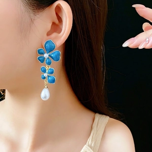 Vintage royal blue enamel flower earrings with pearls shown on model with black background