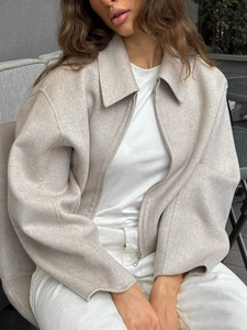Dettaglio della giacca beige con zip, maniche ampie, colletto a revers e texture lana
