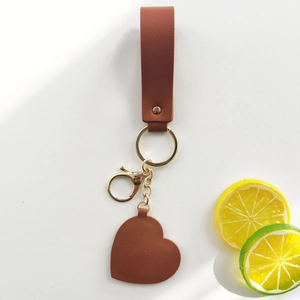 Brown leather heart-shaped mirror keychain with golden metal ring and strap detail