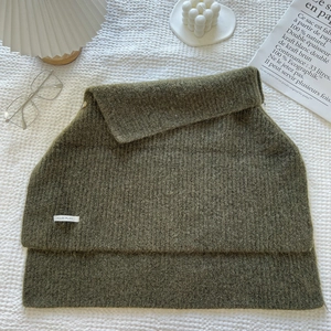 Detail of olive green ribbed knit collar showing texture and brand label on white surface