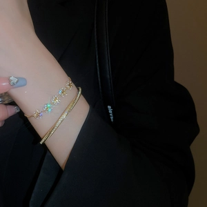 Detail of gold-plated flower bracelet and pavé zircon bangle worn on female wrist