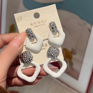Detail view of silver geometric earrings set with white resin charms and textured metal