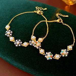 Detail of gold floral bracelets with pearls and colorful crystals on green velvet
