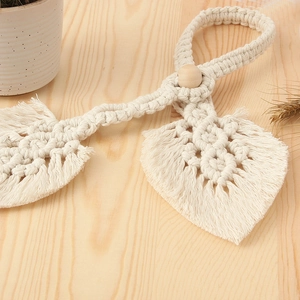 Detail of handcrafted bohemian cotton curtain tieback with leaf shape and wooden bead