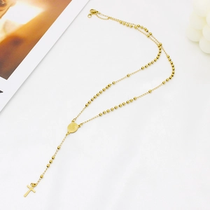 Detail of gold cross pendant necklace featuring virgin mary medal and rosary style beads