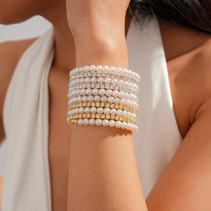 Detail of multi-layer faux pearl and rhinestone beaded bracelets on a woman's wrist