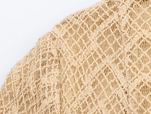 Detailed macro shot of beige hollow-out knitted lace fabric with diamond mesh pattern