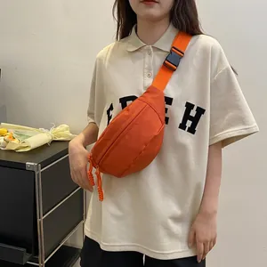 Detail of bright orange nylon crossbody bag with adjustable strap and plastic buckle