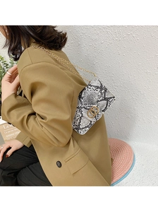 Detail of snake print pattern and gold double ring buckle on a stylish crossbody bag