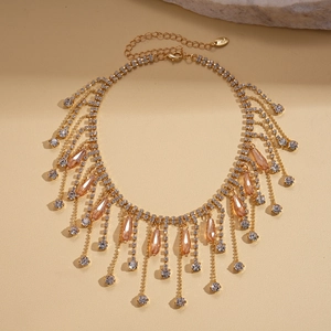 Gros plan du collier à pampilles dorées avec cristaux champagne et strass blancs