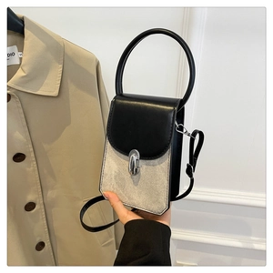 Detail of a beige canvas and black PU leather mini bag with a metal clasp and shoulder strap